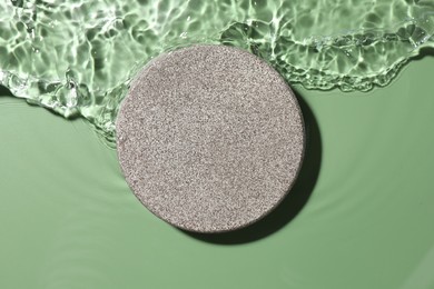 Photo of Presentation for product. Stone podium in water on green background, top view