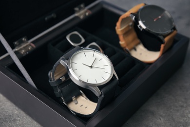 Photo of Case with stylish wrist watches on gray background. Fashion accessory