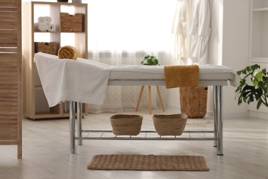 Photo of Comfortable massage table with clean towels in spa center