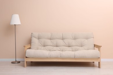 Photo of Comfortable sofa and stylish lamp near beige wall indoors