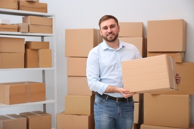 Photo of Young businessman with cardboard box at warehouse