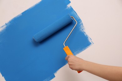 Photo of Woman painting wall with roller, closeup. Redecoration
