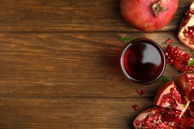 Photo of Pomegranate juice in glass and fresh fruits on wooden table, flat lay. Space for text