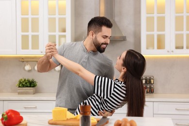 Photo of Happy lovely couple dancing together while cooking in kitchen