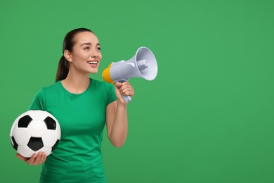 Photo of Happy fan with soccer ball using megaphone on green background, space for text