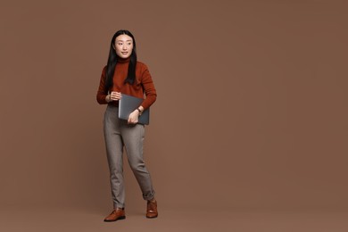 Photo of Full length portrait of smiling woman with laptop on brown background. Space for text