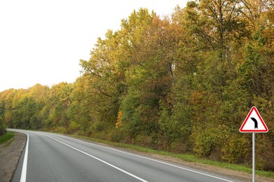 Image of Traffic sign BEND TO LEFT near empty asphalt road in autumn