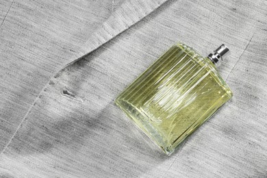 Photo of Luxury men's perfume in bottle on grey jacket, top view. Space for text