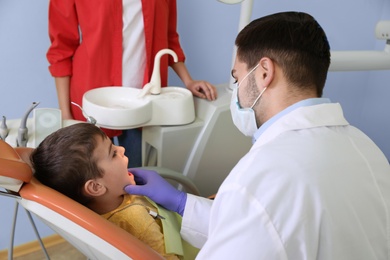 Photo of Professional dentist working with little patient in modern clinic
