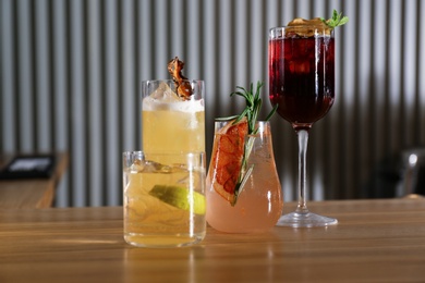 Photo of Glasses of delicious cocktails with vodka on wooden counter in bar