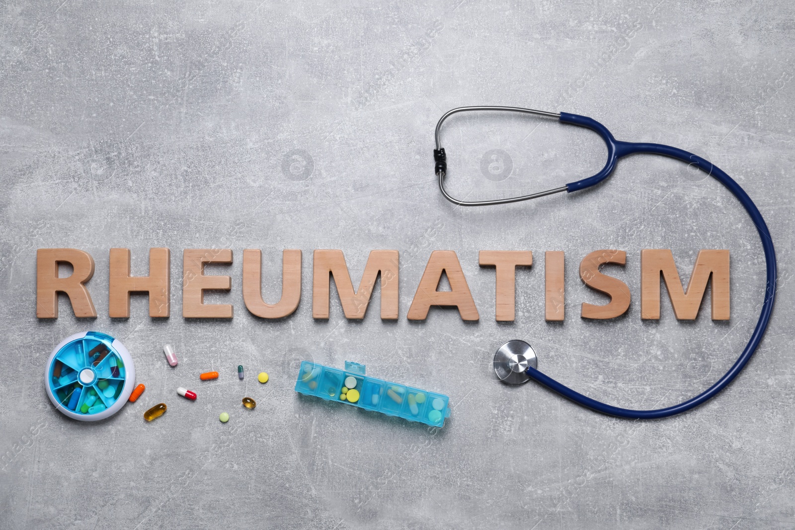 Photo of Word Rheumatism made of wooden letters, stethoscope and pills on light gray textured background, flat lay