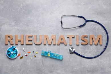 Word Rheumatism made of wooden letters, stethoscope and pills on light gray textured background, flat lay
