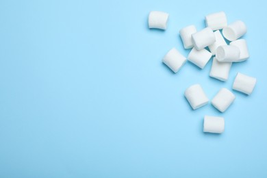 Photo of Delicious puffy marshmallows on light blue background, flat lay. Space for text