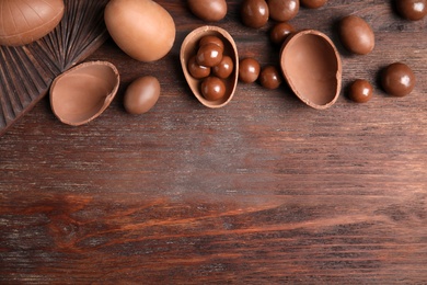 Photo of Tasty chocolate eggs and candies on wooden table, flat lay. Space for text