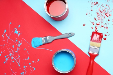 Photo of Flat lay composition with paint cans and brushes on color background