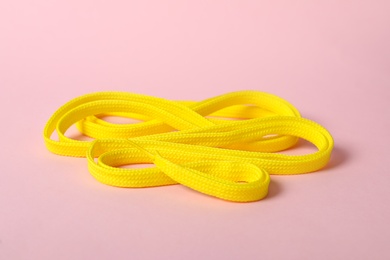 Photo of Yellow shoe lace on light pink background