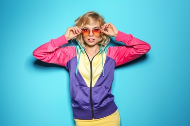 Photo of Stylish young woman with sunglasses posing on color background