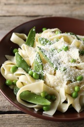 Delicious pasta with green peas and cheese on wooden table