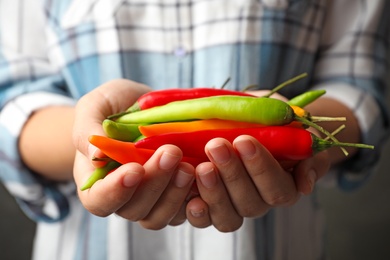 Photo of Young woman holding different hot chili peppers, closeup