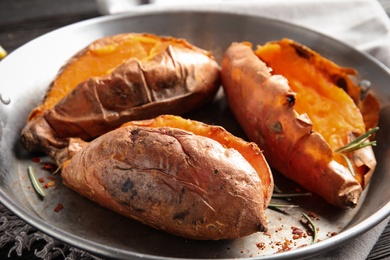 Photo of Dish with baked sweet potatoes on table, closeup
