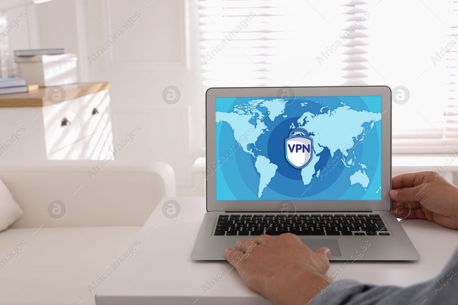 Image of Man using laptop with switched on VPN at white table indoors, closeup