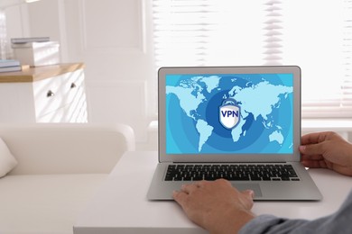 Image of Man using laptop with switched on VPN at white table indoors, closeup
