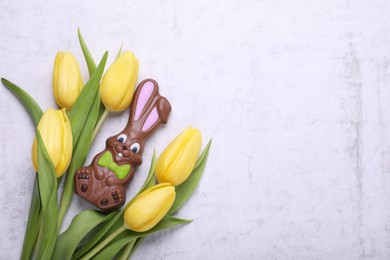 Photo of Flat lay composition with chocolate Easter bunny and beautiful tulips on white textured table. Space for text