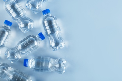 Photo of Bottles of water on light background, top view. Space for text