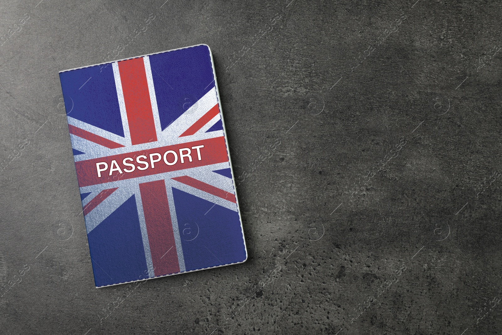 Image of Passport in case with image of UK flag on dark grey table, top view. Space for text