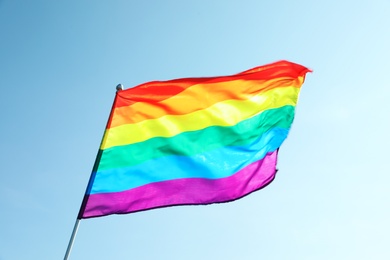 Photo of Rainbow gay flag against blue sky. LGBT concept