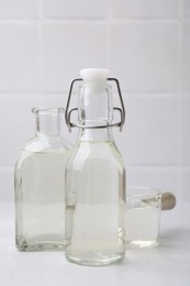 Photo of Vinegar in glass bottles and saucepan on light table