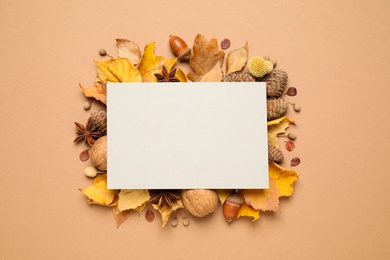 Photo of Flat lay composition with autumn leaves and blank card on beige background, space for text