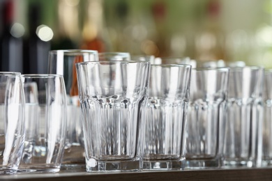 Photo of Empty glasses on wooden table against blurred background