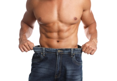 Photo of Young man with slim body in old big size jeans on white background, closeup view