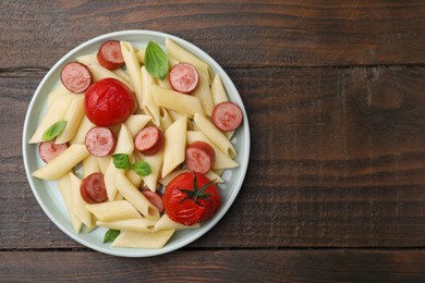 Photo of Tasty pasta with smoked sausage, tomatoes and basil on wooden table, top view. Space for text