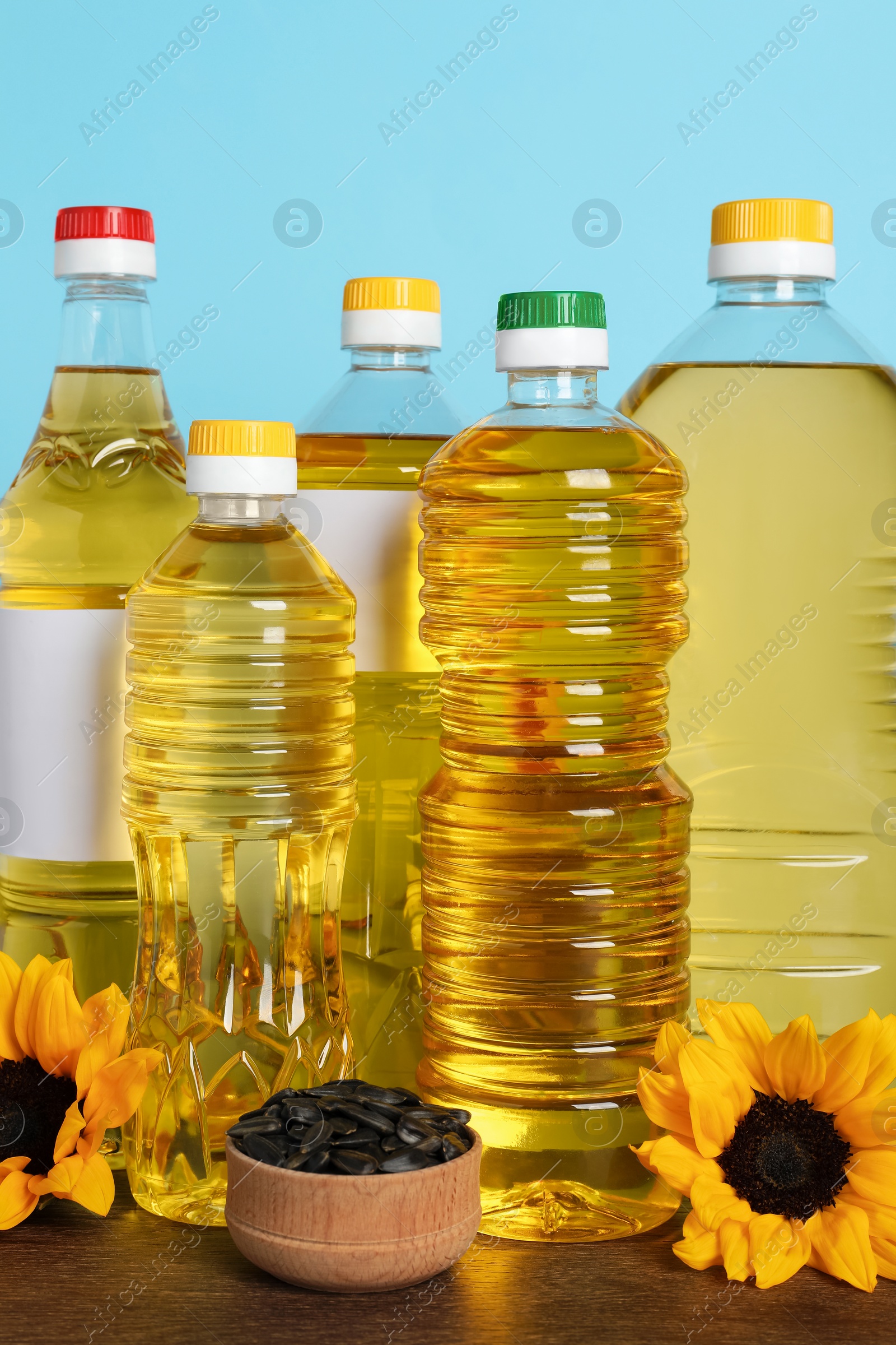Bottles of cooking oil, sunflowers and seeds on wooden table Photo of Bottles of cooking oil, sunflowers and seeds on wooden table