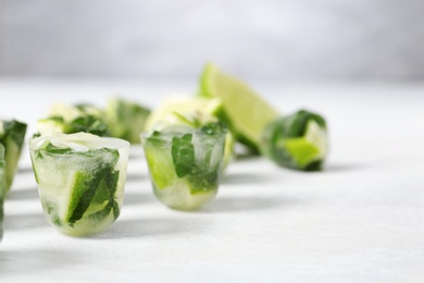 Photo of Lime and mint ice cubes on light table. Space for text