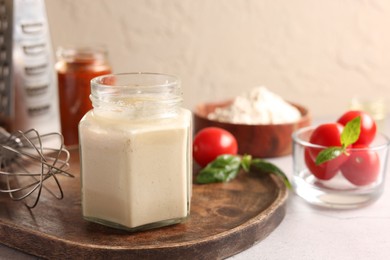 Photo of Pizza dough starter in glass jar, products and whisk on gray table
