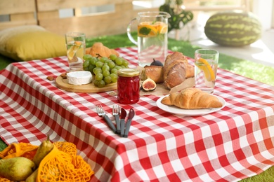 Photo of Different tasty food on picnic blanket at home