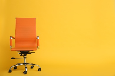 Photo of Modern office chair on yellow background. Space for text