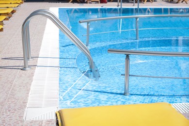 Photo of Outdoor swimming pool with ladder and handrails on sunny day