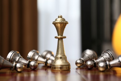 Photo of Queen piece among defeated pawns on chessboard indoors