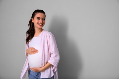Young pregnant woman on light grey background. Space for text