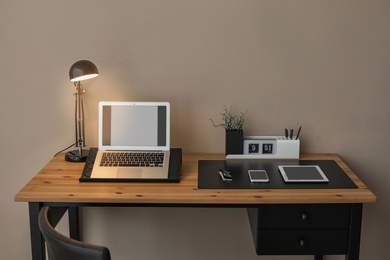 Photo of Modern workplace interior with laptop and devices on table. Space for text