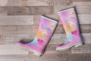 Photo of Pair of gumboots on wooden background, top view. Female shoes