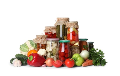 Photo of Fresh vegetables and jars of pickled products on white background