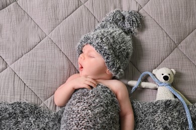 Cute newborn baby with toy yawning in bed, top view