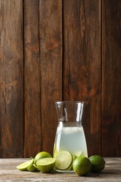 Photo of Natural lemonade with lime in bottle on wooden table