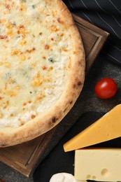 Photo of Delicious cheese pizza, tomato and different kinds of cheese on dark grey table, flat lay