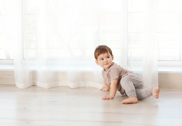 Photo of Cute baby crawling on floor at home